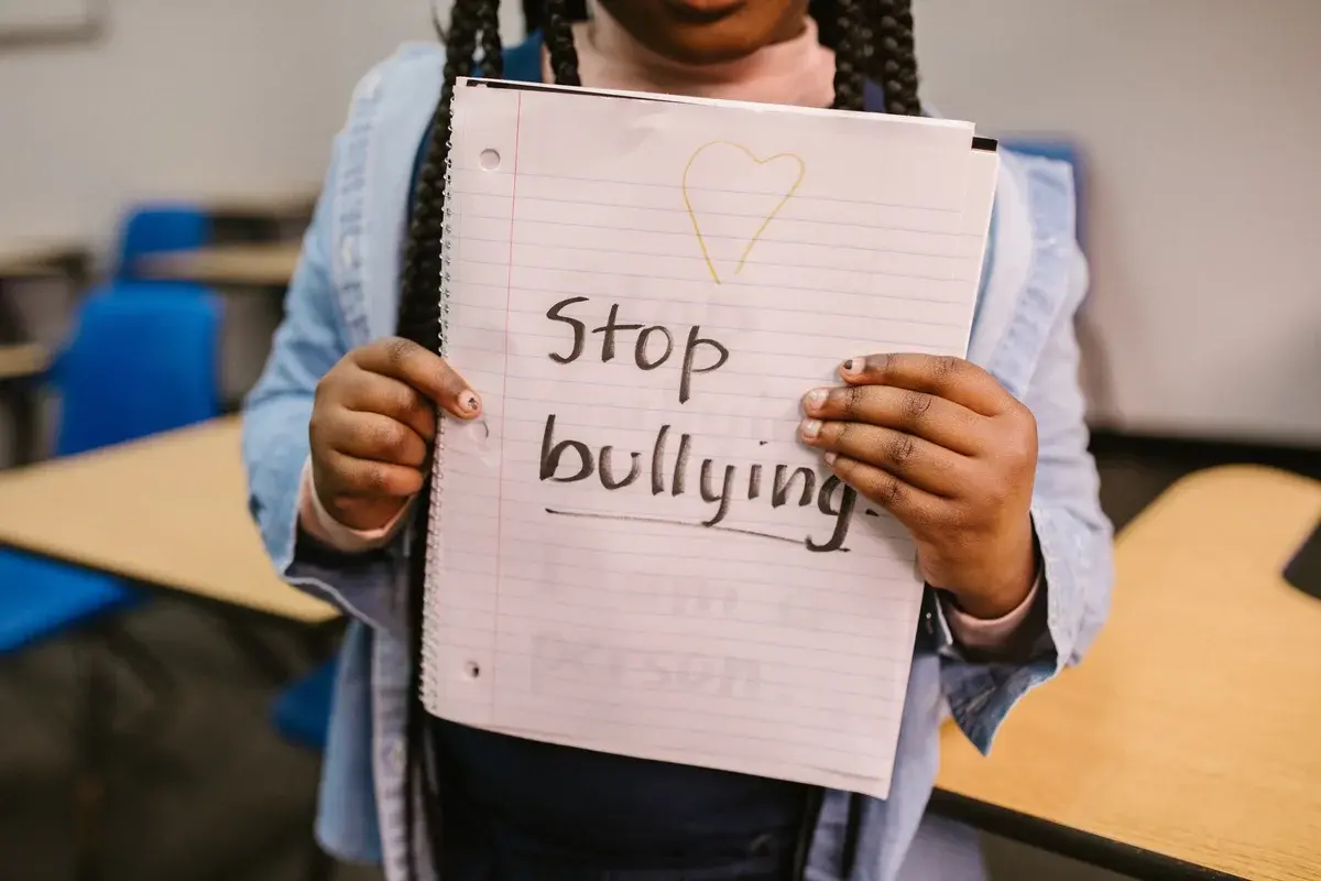 young girl holding stop bullying sign on notebook paper