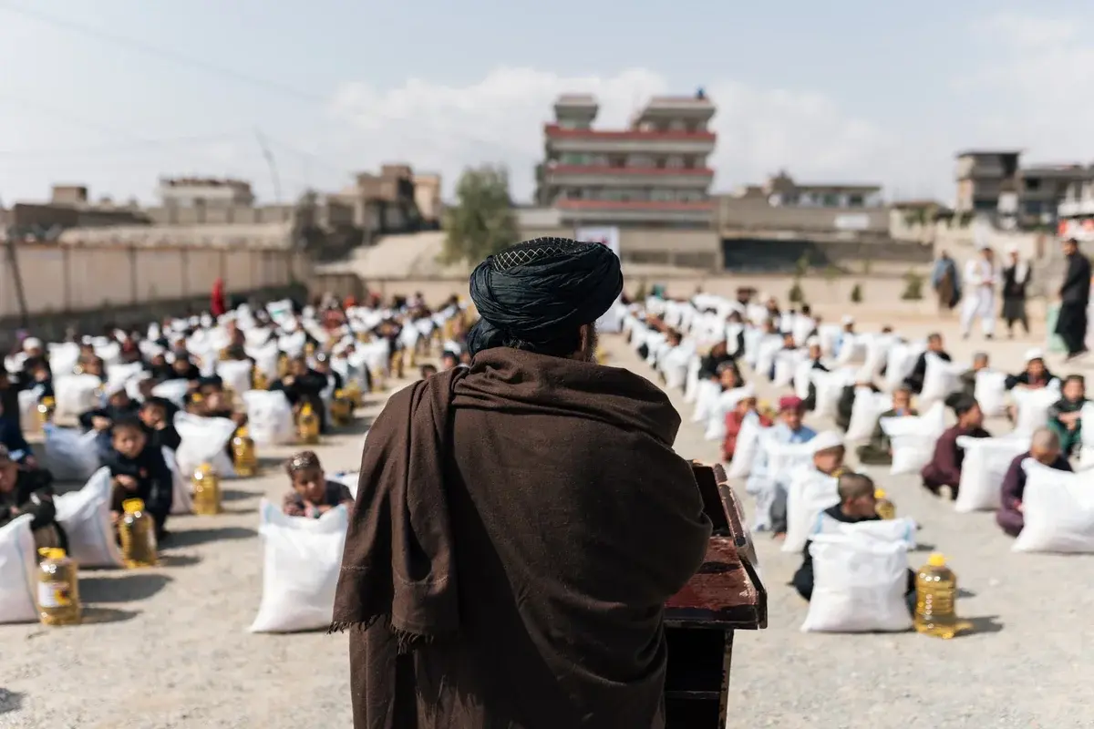 People seated with aid supplies in rows outdoors