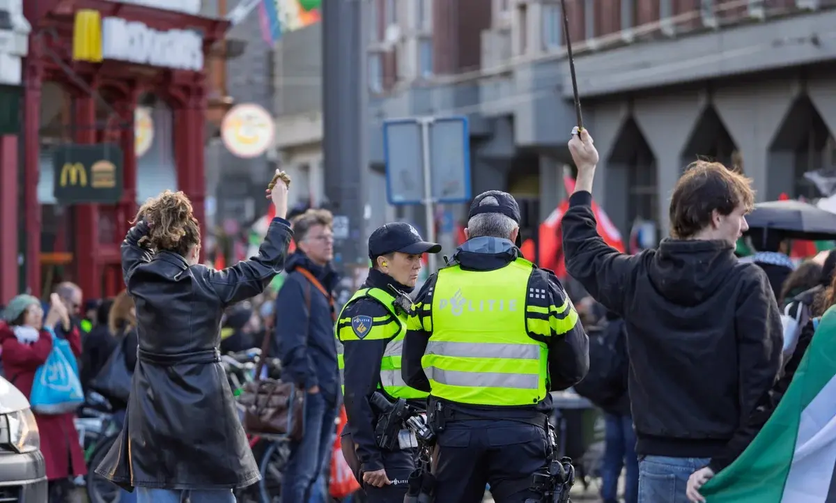 Police officers watch a peaceful protest in a city street.