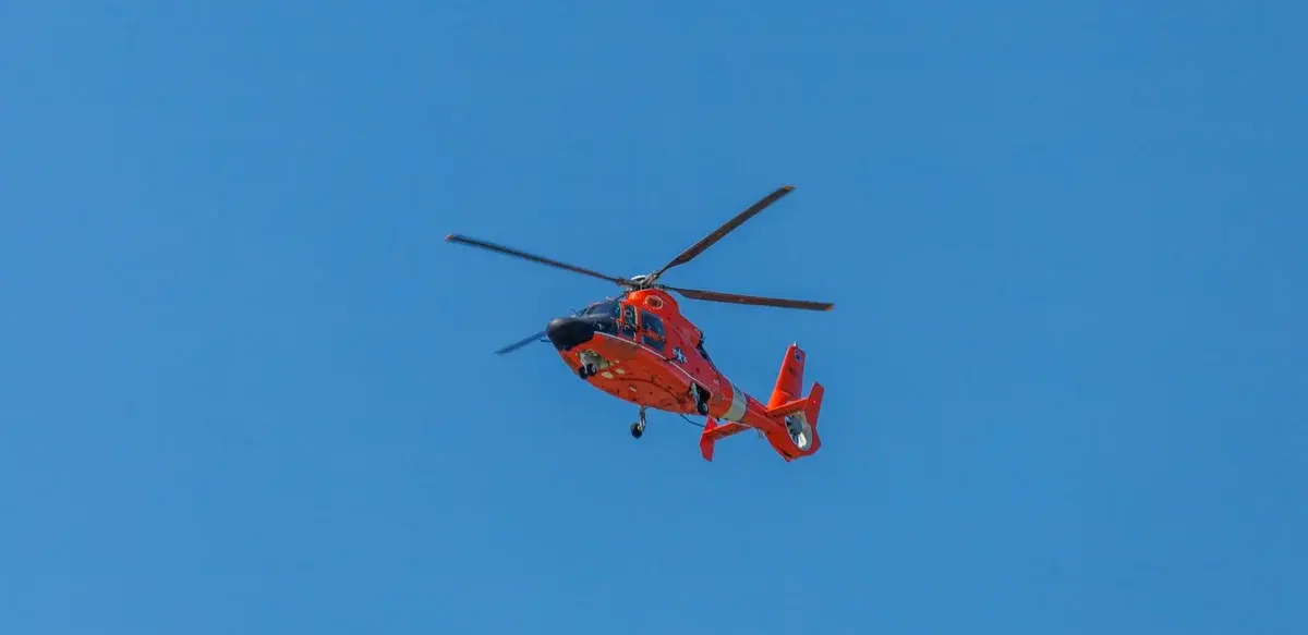 Red helicopter flying in clear blue sky