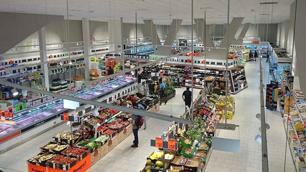 Interior of a Lidl supermarket with produce aisles and shoppers.