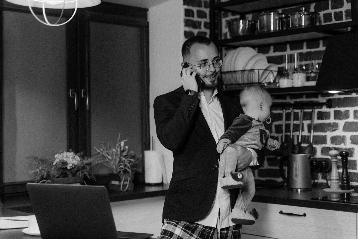 Father holding baby and talking on phone in kitchen