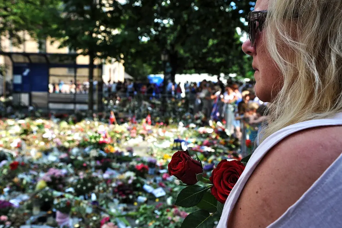 Woman holding roses at a crowded flower memorial