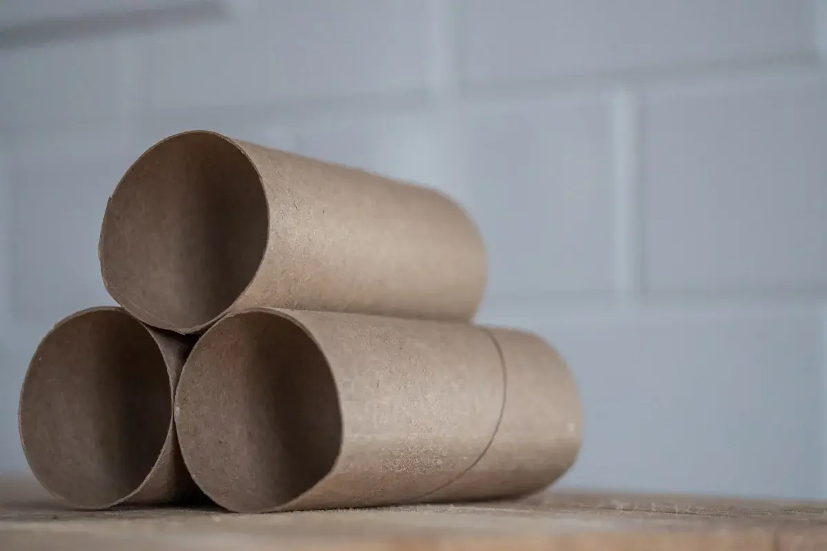 Close-up of stacked brown toilet paper cardboard tubes on a wooden table.