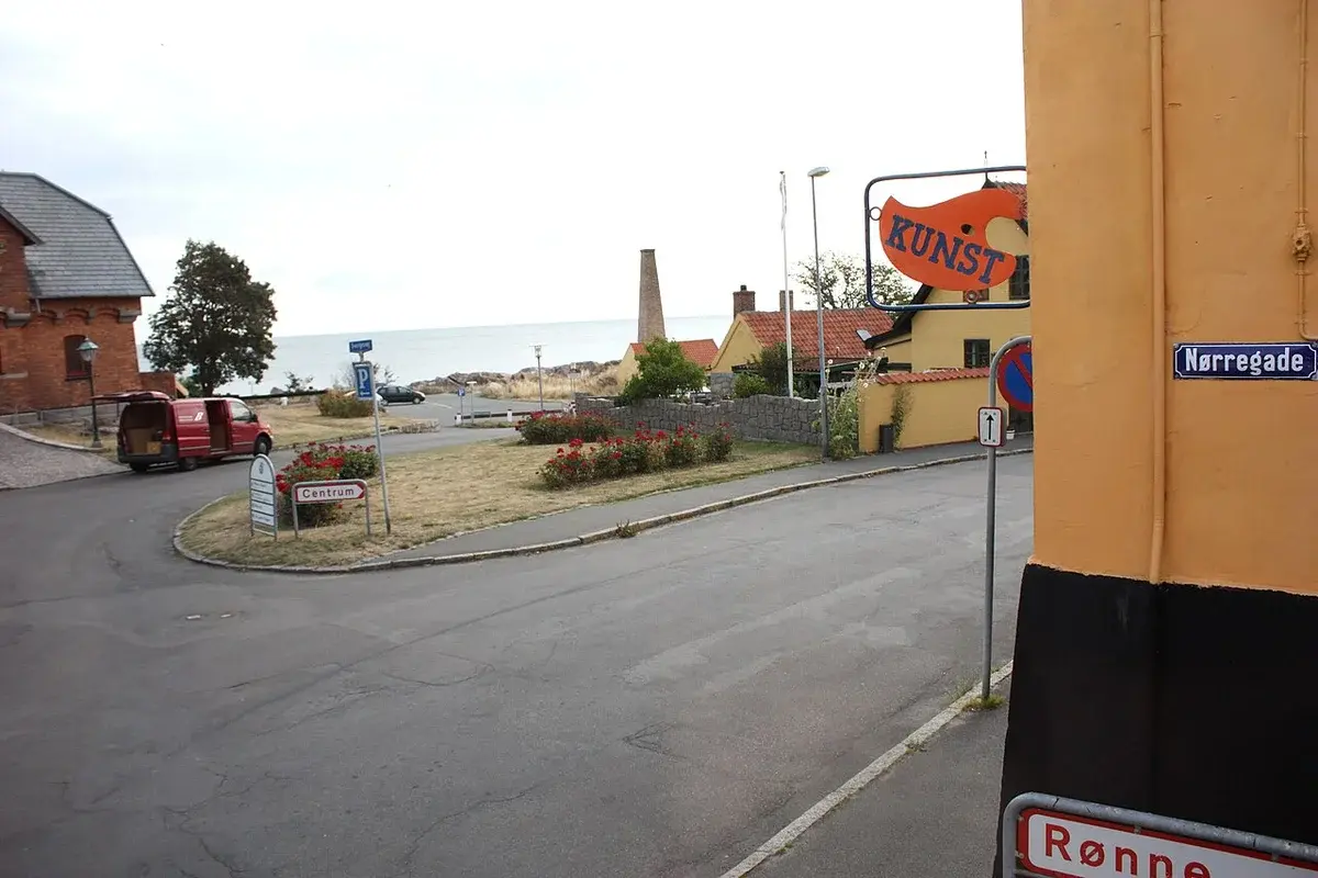 Street corner in a coastal Danish town with road signs and the sea in the distance.