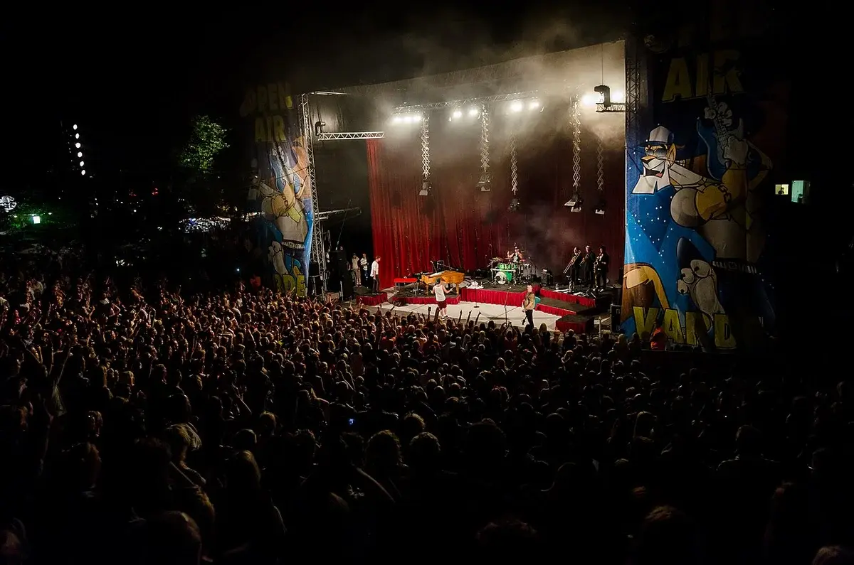 Crowd watching a live performance on an outdoor festival stage at night.
