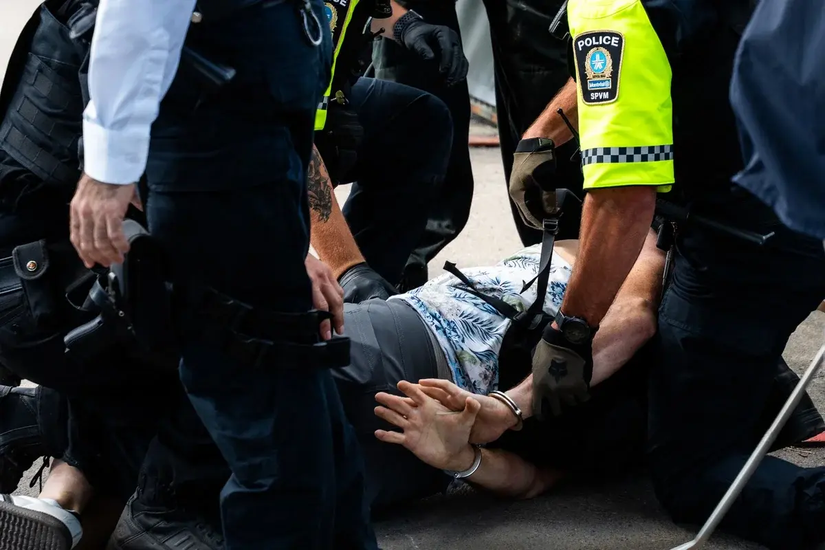 Police officers handcuff a person on the ground during an arrest