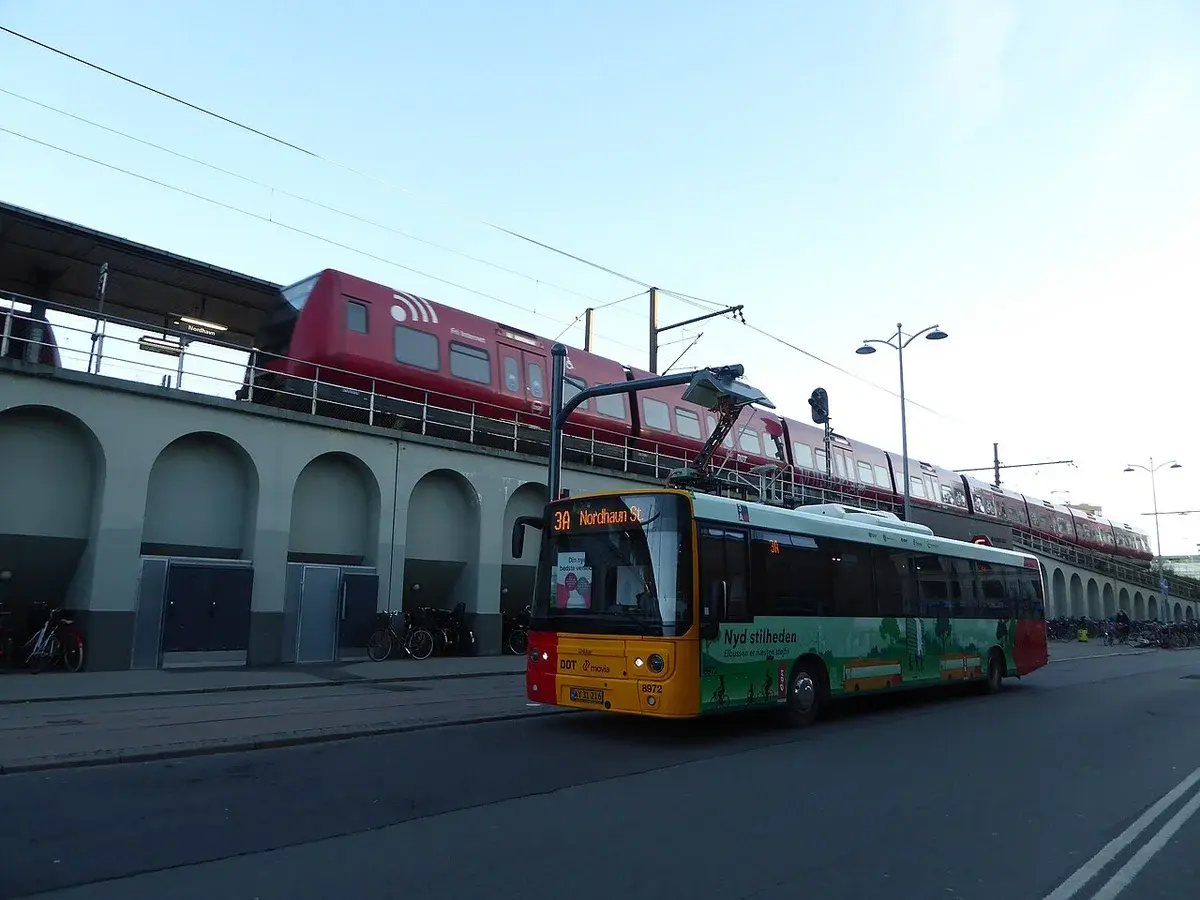Electric bus on Movia line 3A at Nordhavn Station with a red S-train in the background