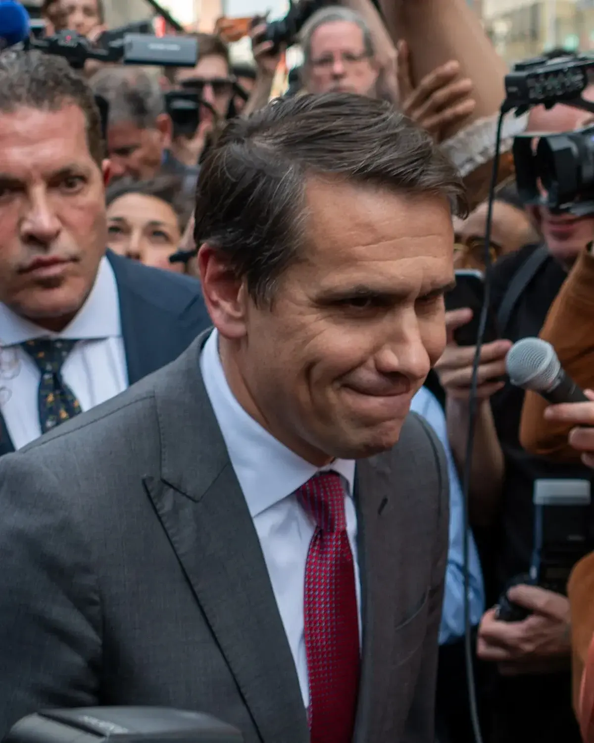 Man leaving crowd of reporters outside courthouse