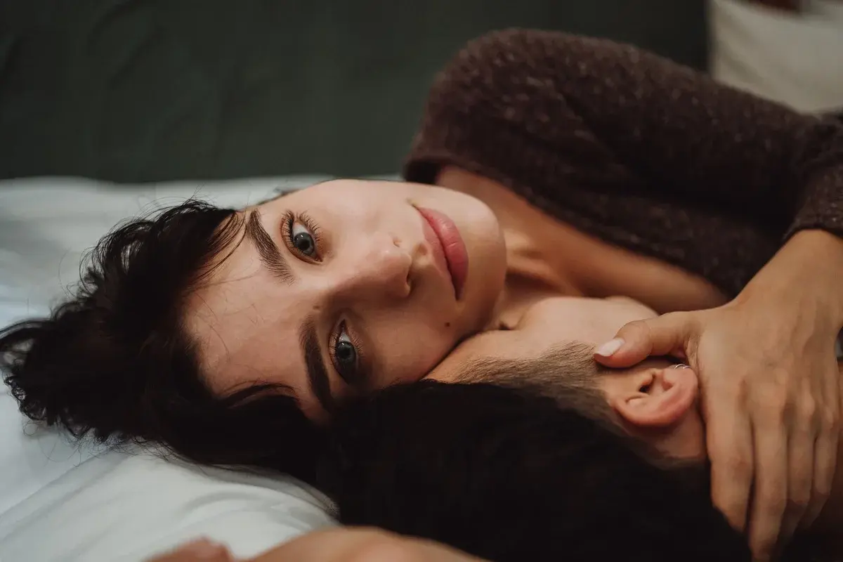 Close-up of a couple cuddling on a bed indoors.