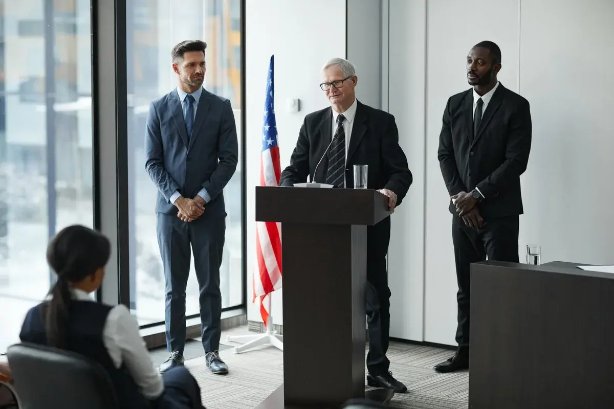Officials giving political speech with American flag behind