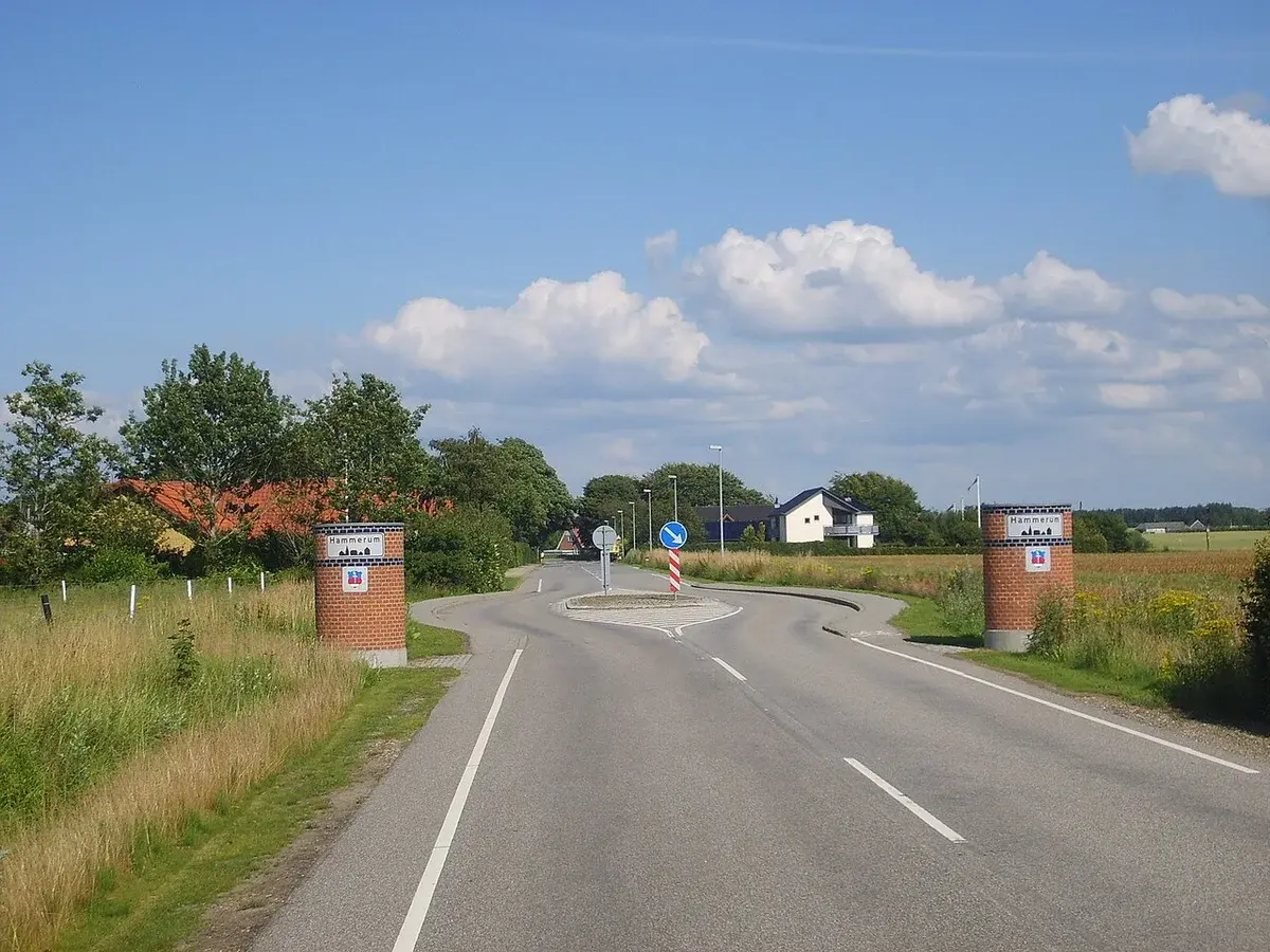 Rural road entrance with signs for Hammerum and a small roundabout.