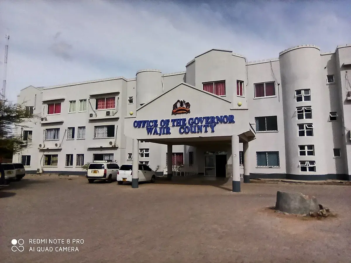 Government building in Wajir County, Kenya with parked cars.
