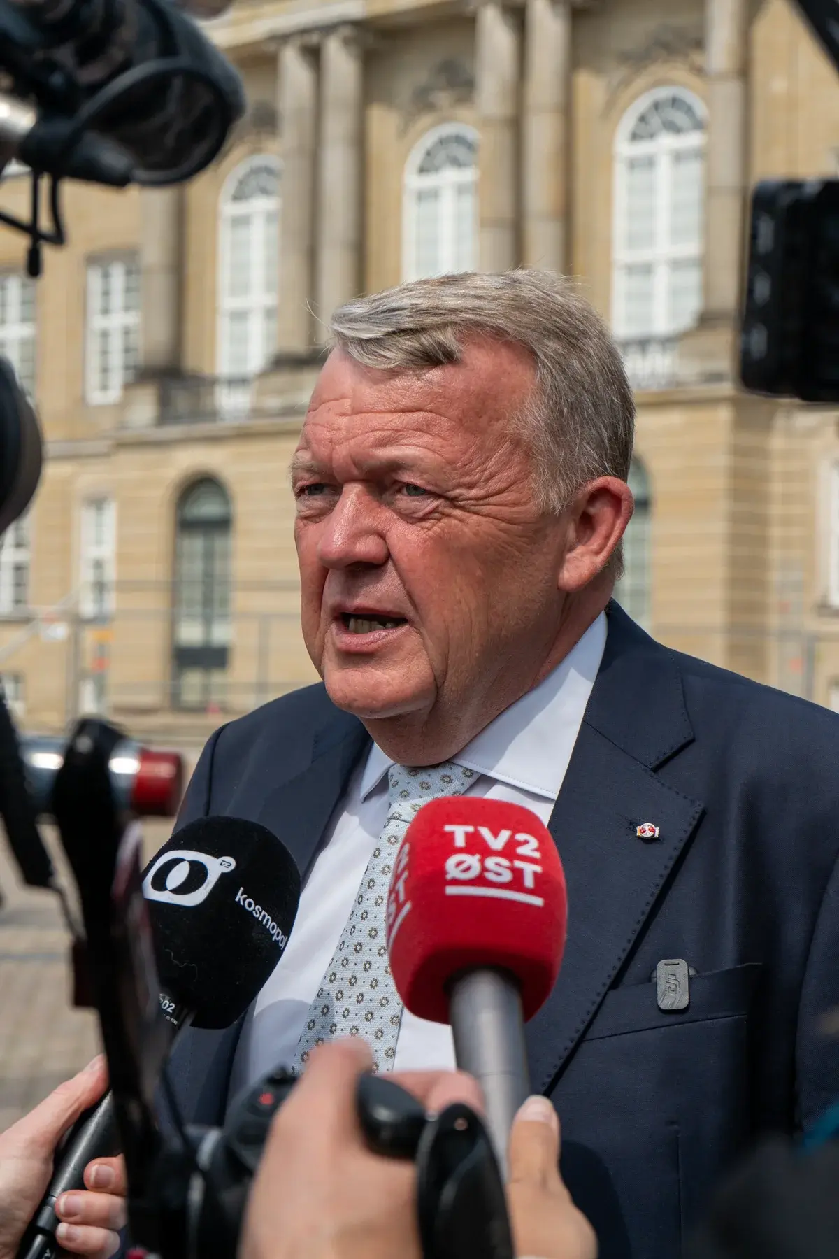 Man giving an interview to reporters outside a historic building