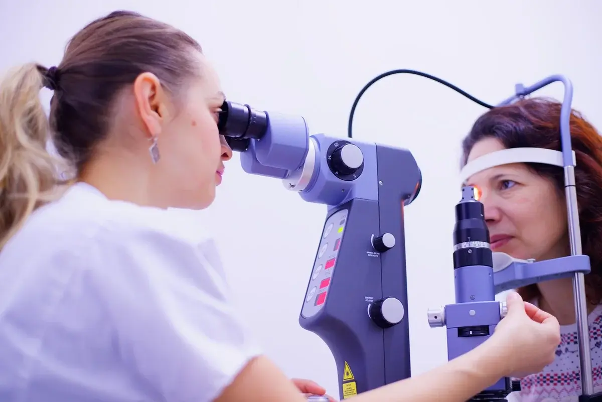 Doctor performing an eye exam on a woman using a slit lamp microscope