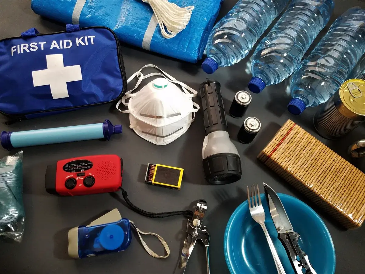 Survival emergency kit with first aid kit, water, canned food, flashlight, radio, and utensils