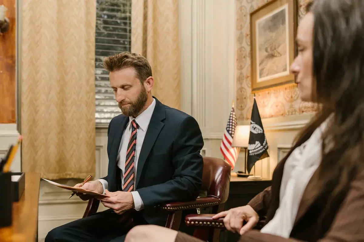 A lawyer in a suit reviews documents during an office meeting.