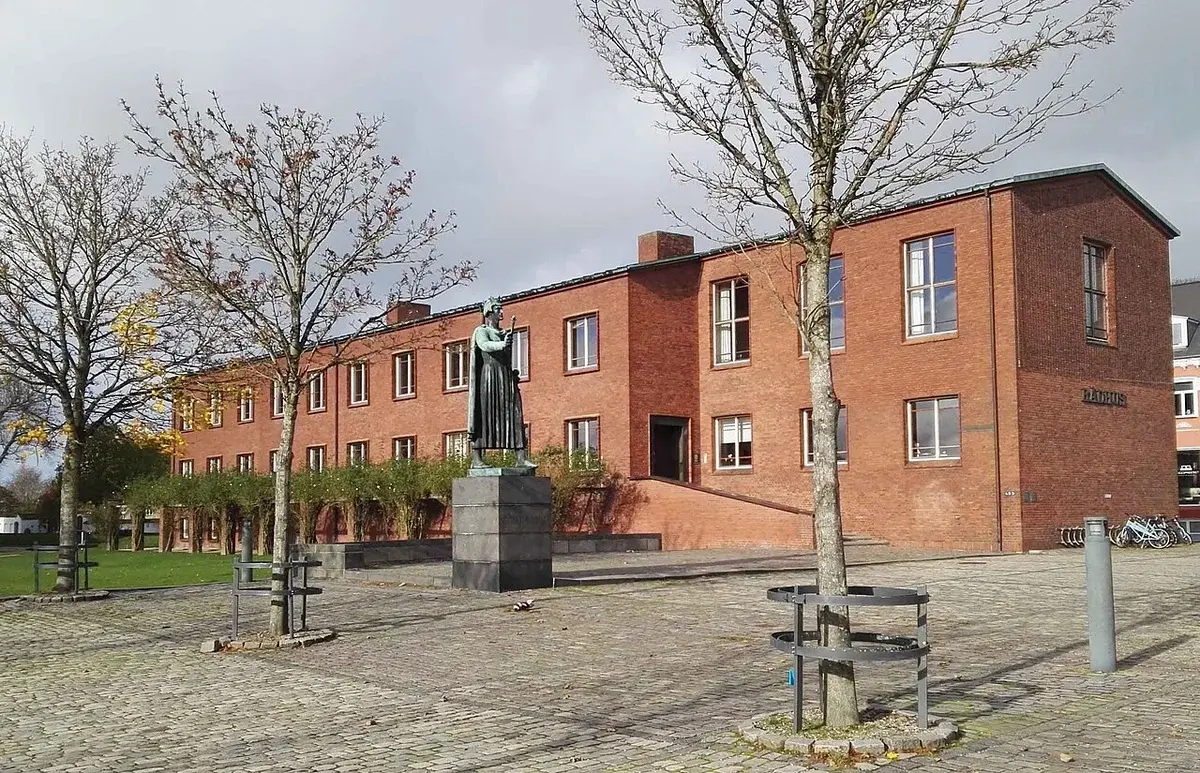 Red brick town hall building with statue and trees