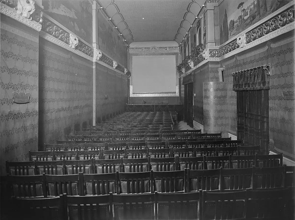Black and white photo of the interior of Kinografen movie theater with rows of chairs and ornate walls