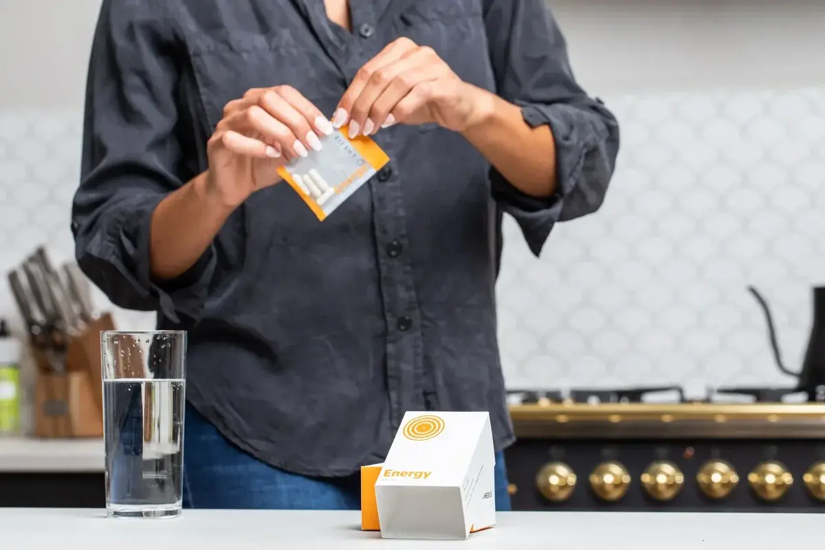 Person opening energy supplement packet in kitchen