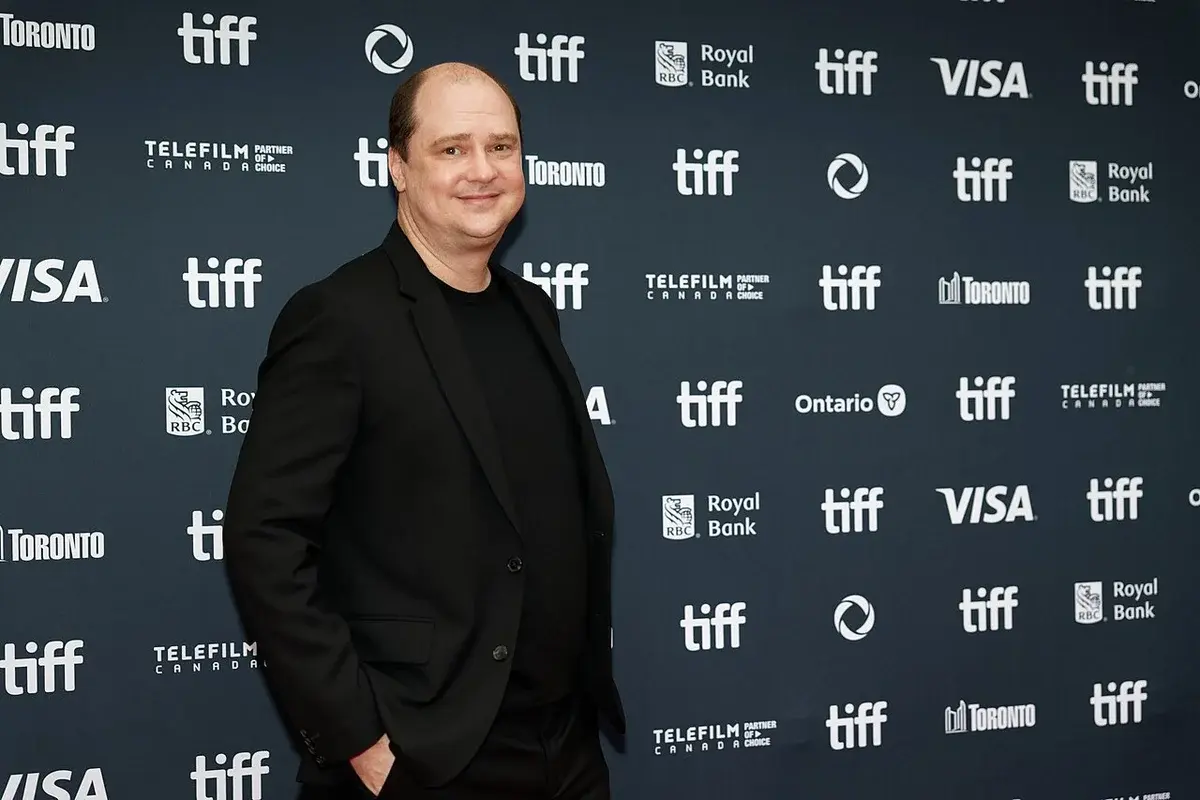 Mike Flanagan posing at TIFF 2024 in front of a branded backdrop.