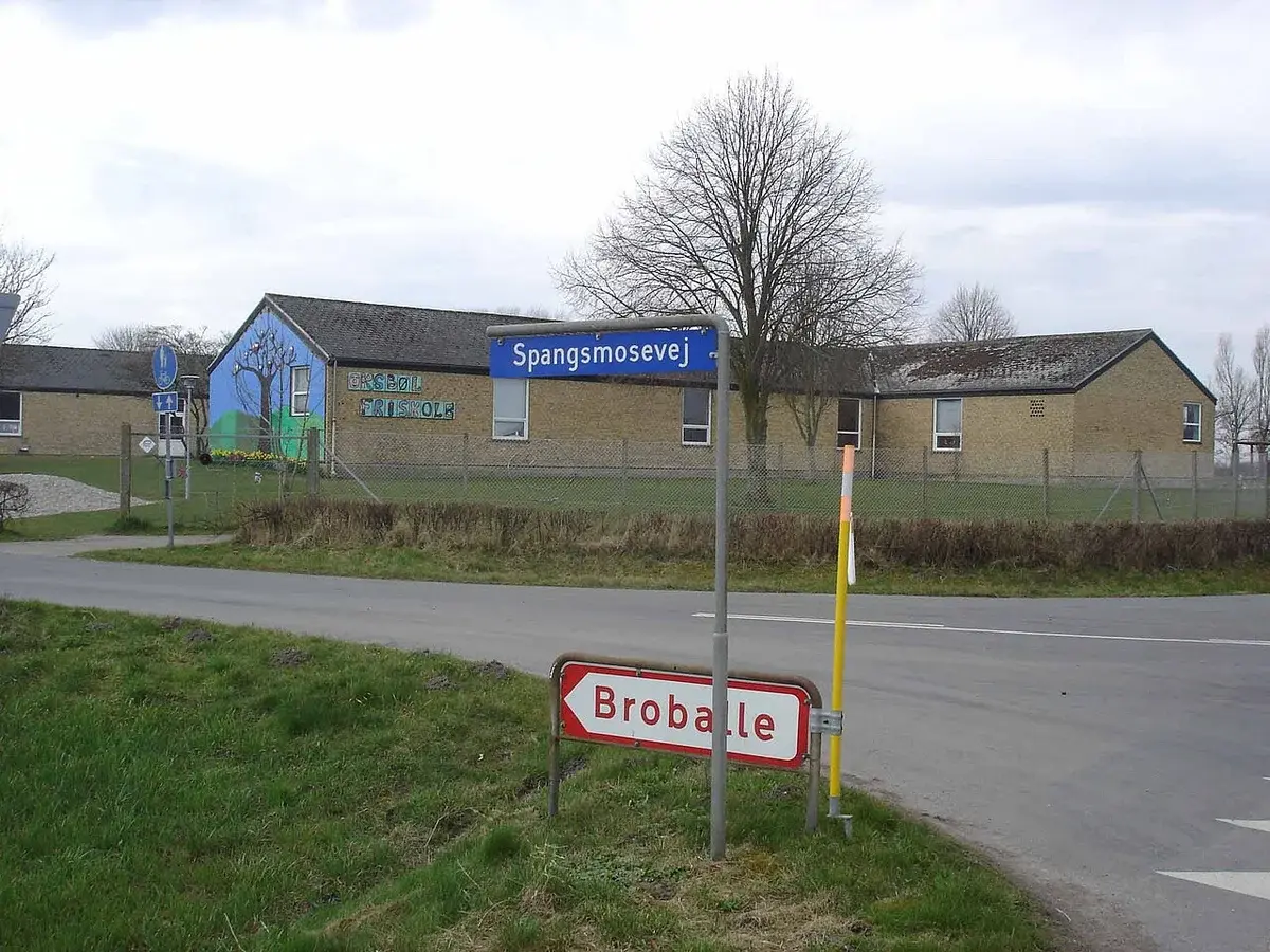 School building at a rural road intersection with street signs