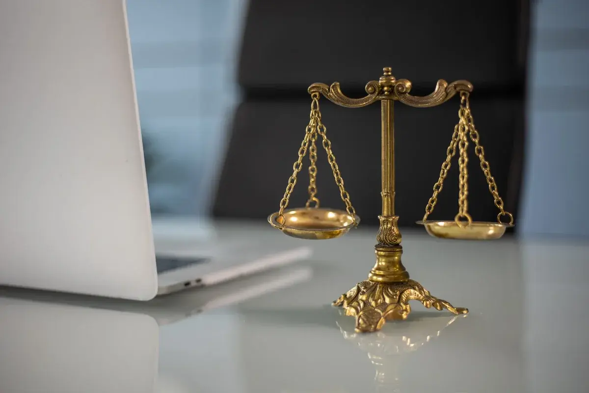 Golden justice scales on desk beside laptop
