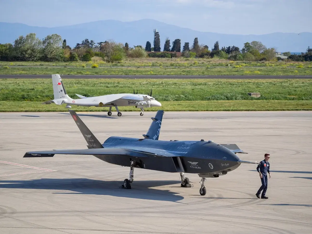 Two advanced military drones on an airport runway with personnel