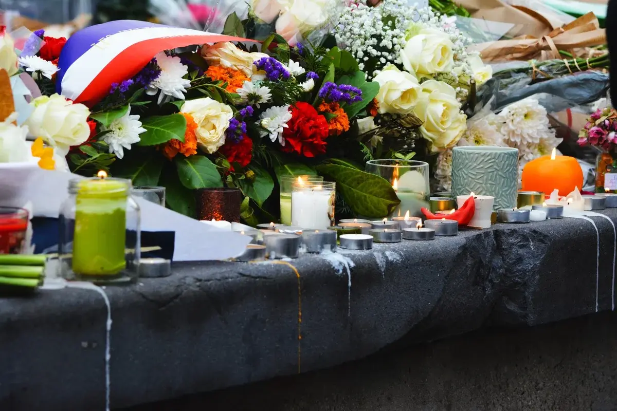 lit candles and flowers on stone memorial