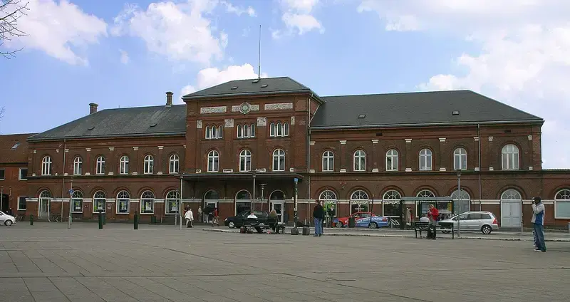 Facade of Kolding Railway Station with people and cars in front
