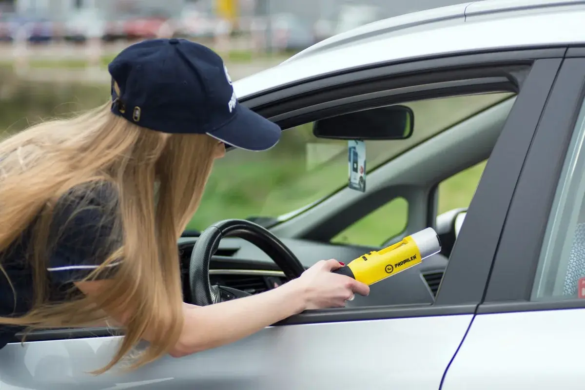 Female officer holding yellow device near car window