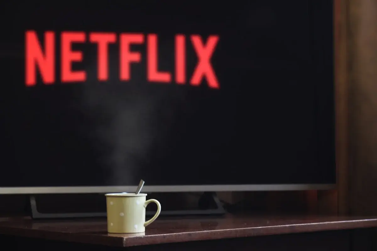 Steaming cup on table in front of TV showing Netflix logo
